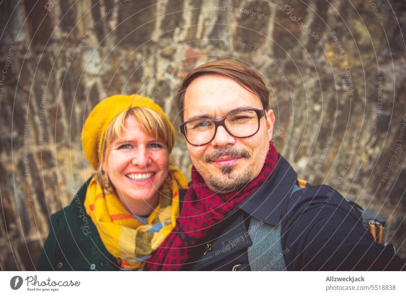 glückliches Pärchen in herbstlicher Kleidung macht ein Selfi vor einer Mauer selfie Paar Paare Paare mittleren Alters pärchen Herbst deutschlandreise heimurlaub