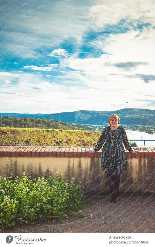 junge Frau in Kleid steht vor einer Mauer mit Panorama Ausblick in Koblenz Herbst herbstlich deutschlandreise heimurlaub sympathisch adrett modisch Herbstlaub