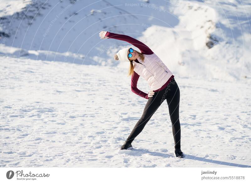 Junge Frau steht und macht Übungen im Schnee im Hochland Erholung Winter Berge u. Gebirge Verschlussdeckel Dehnung Landschaft jung Sonnenbrille Outfit
