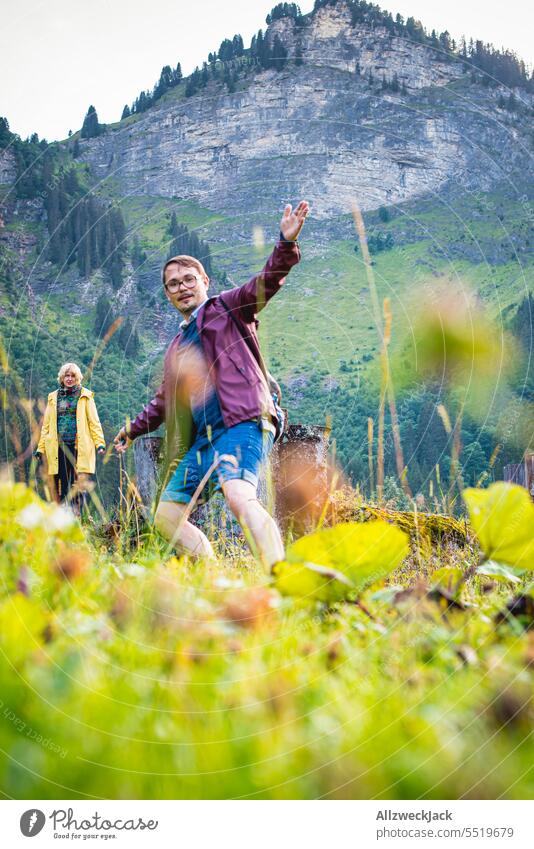 junges Pärchen mit Regenjacken beim wandern auf einer schweizer Alm Schweiz Schweizer Alpen Wiese Natur grün saftig saftiges grün Tal Bäume nass Landschaft