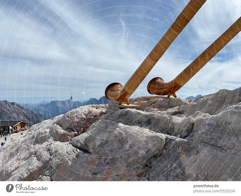 Zwei Alphörner auf Felsen unter freiem Himmel im September 2023 auf der Zugspitze. Foto: Alexander Hauk Musik Musikinstrumente Lied Lieder Alphorn Alhörner blau