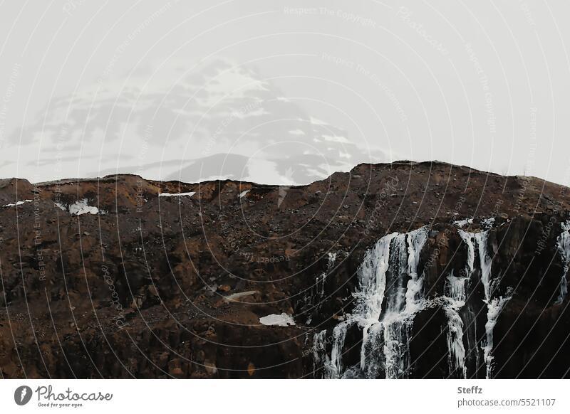 Wasserfall mit einem Berggipfel im Hintergrund auf Island Ostisland isländisch isländische Natur Naturerlebnis Berge Felsen isländische Wasserfälle frostig