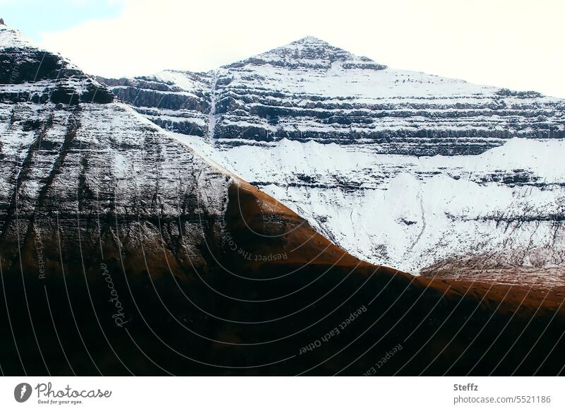 Färöer Inseln mit schneebedeckten Gipfeln Färöerinseln Färöer-Inseln Schafsinseln Felsen spektakulär Felshügel Felsenwand Felsufer Hügel Hügelseite verschneit