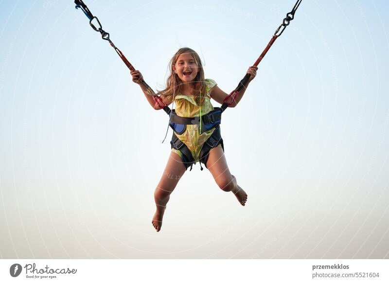 Bungee-Springen auf dem Trampolin. Kleines Mädchen hüpft auf Bungee-Springen im Vergnügungspark auf Sommerferien springend Vergnügen Park Ferien Spielen spielen