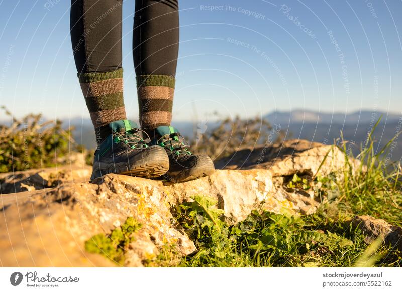 Detail der Stiefel eines Wanderers auf dem Gipfel eines Berges, mit unscharfer Naturlandschaft im Hintergrund Berge u. Gebirge Wanderung reisen Abenteuer Fuß