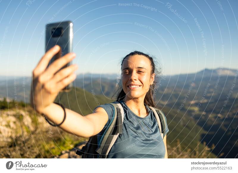 Eine junge, glückliche Frau lächelt, als sie ein Selfie mit ihrem Smartphone vom Gipfel eines Berges macht Frauen Person Lifestyle Glück Schönheit Mobile