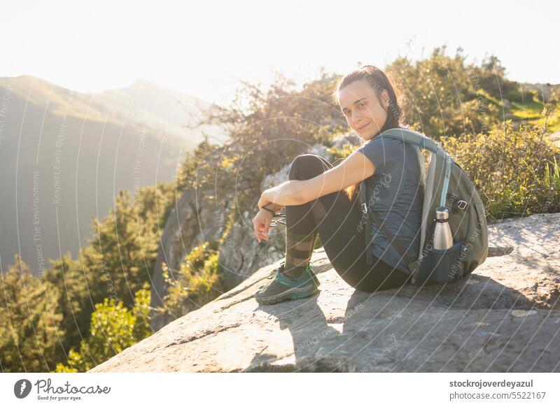 Eine junge Frau, Bergsteigerin, ruht sich auf dem Gipfel eines Berges aus, im Hintergrund die unscharfe Naturlandschaft Berge u. Gebirge Reisender Abenteuer