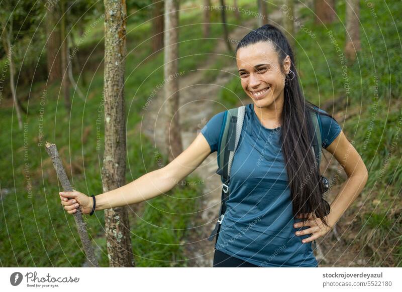 Eine junge Wanderin mit einem Holzstock als Wanderstock lächelt und genießt eine Pause während einer Wanderung in der Natur Frau Person Lifestyle Fröhlichkeit