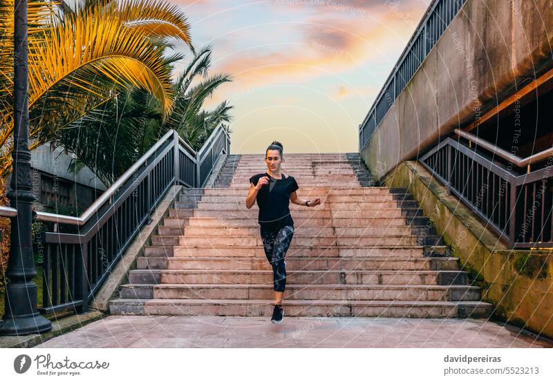 Weibliche Läuferin trainiert die Treppe hinunter in einer städtischen Startbahn bei Sonnenuntergang Frau Glück Training Treppenhaus Schritt nach unten genießen