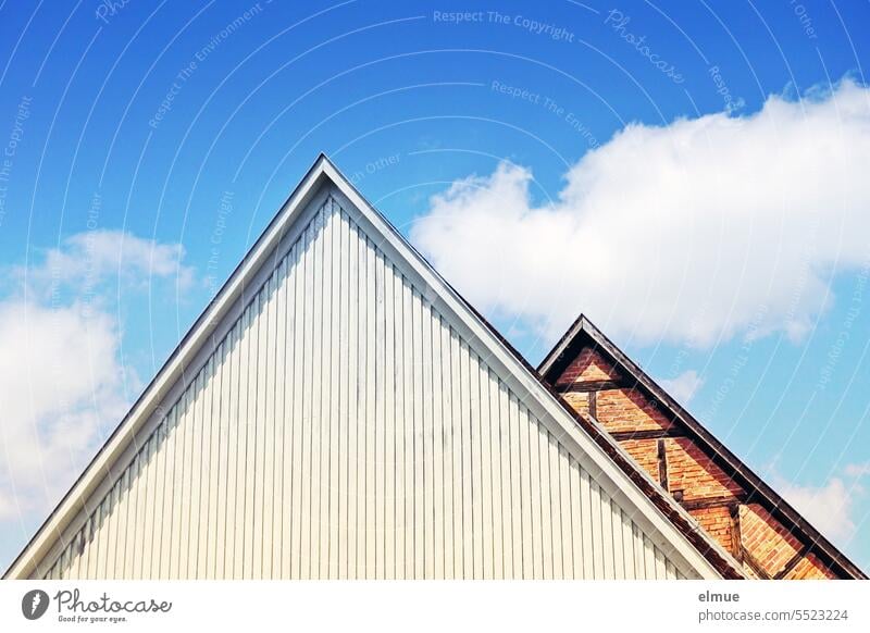 zwei unterschiedliche, fensterlose Dachgiebel - holzverkleidet und Fachwerk vor blauem Himmel mit Schönwetterwolken Giebelwand Stirnseite Haus Architektur
