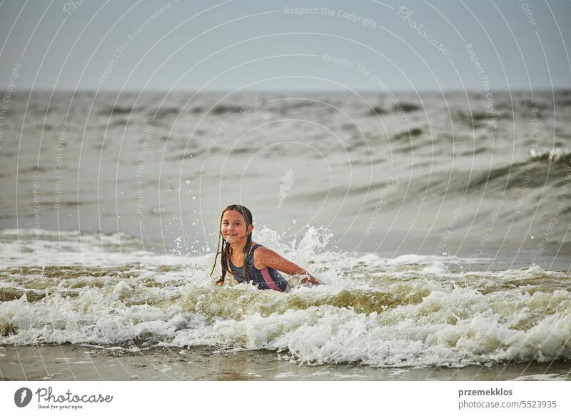 Kleines Mädchen spielt mit Wellen im Meer. Kind plantscht spielerisch in Wellen. Kind springt ins Meer. Urlaub am Strand. Wasser plätschert Sommer Ferien MEER