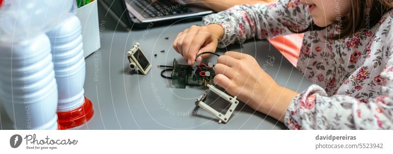 Schülerin beim Anschließen von Drähten an einen Stromkreis im Robotikunterricht unkenntlich Kinder Frau verbindend Kabel Draht elektronisch elektrisch