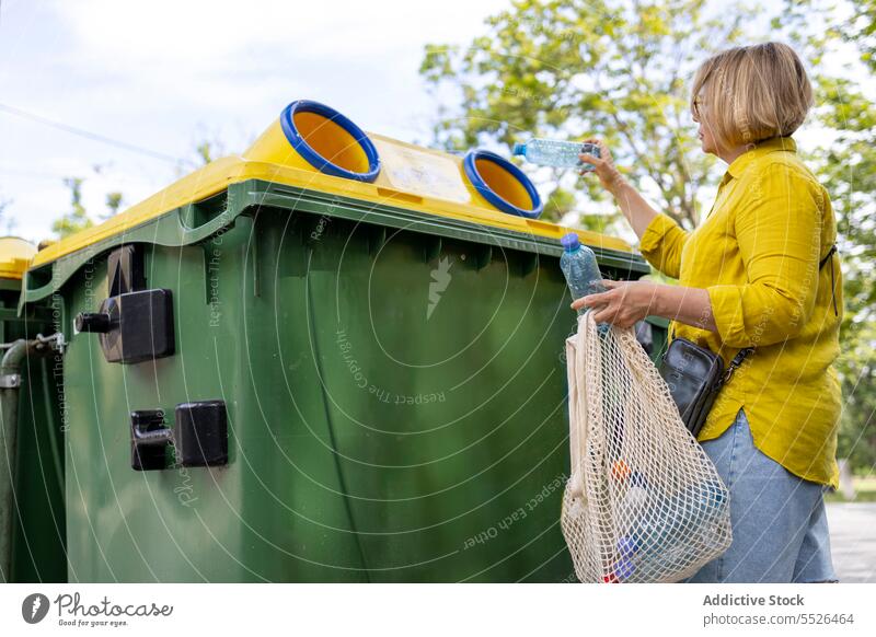 Frau wirft Müll in die gelbe Tonne wiederverwerten Kunststoff führen Ökologie Problematik lässig Tageslicht Abfall Container reduzieren Paket gebrauchen Trödel