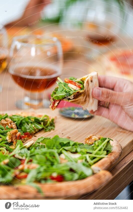 Gesichtslose Person isst Pizza am Tisch in der Nähe von Weingläsern essen Vegetarier Salat Fastfood Walnussholz Glas Lebensmittel appetitlich lecker gebacken
