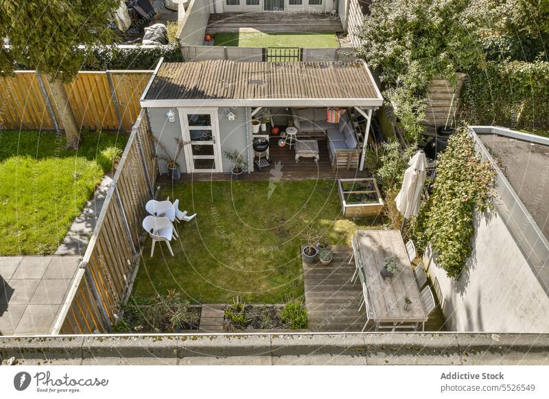 Luftaufnahme eines Hinterhofs mit Garten vor einem kleinen Haus Dach Tisch Stuhl Gras Pflanze Sonnenschirm Möbel patio grün wohnbedingt Gebäude Hof Wiese