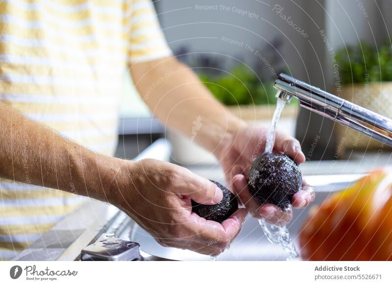 Mann wäscht Avocado unter dem Wasserhahn im Waschbecken Waschen Bestandteil vorbereiten Koch männlich Küche Prozess Vitamin Hausarbeit frisch strömen Sauberkeit