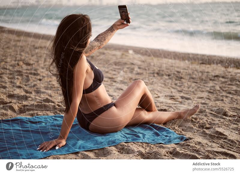Schlanke Frau im Bikini macht Selfie am Strand Smartphone benutzend Sand Decke Sommer Urlaub ruhen Gerät Apparatur sich[Akk] entspannen Badebekleidung