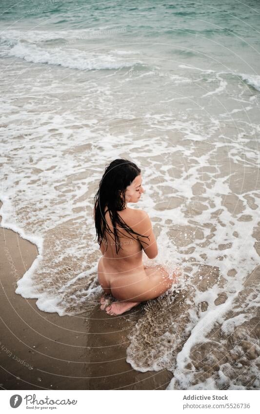 Nackte Frau entspannt sich im Meerwasser am Ufer nackt sinnlich Strand Meeresufer Wasser schäumen Sommer Urlaub MEER nasses Haar Sand Küste knien