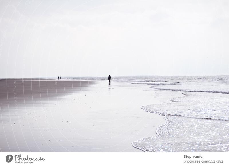 Einsame Spaziergänger am Meer Strand Meeresufer Küste Küstenlandschaft Wellen Mensch Silhouette Sand bewölkt Horizont Ferien & Urlaub & Reisen Landschaft Himmel