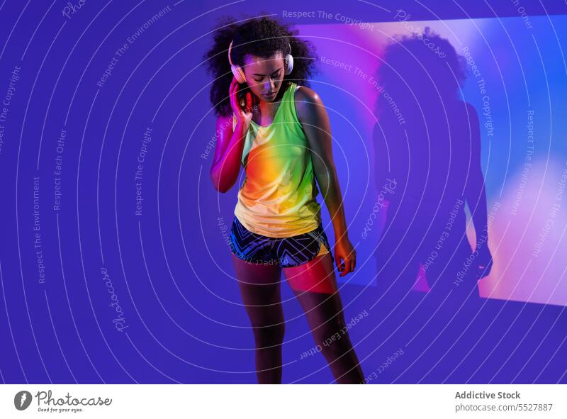 Schwarze Frau mit Kopfhörern im Stehen Studioaufnahme Sport zuhören Musik Fitness schwarz Audio Melodie ethnisch Sportlerin Afroamerikaner meloman Klang