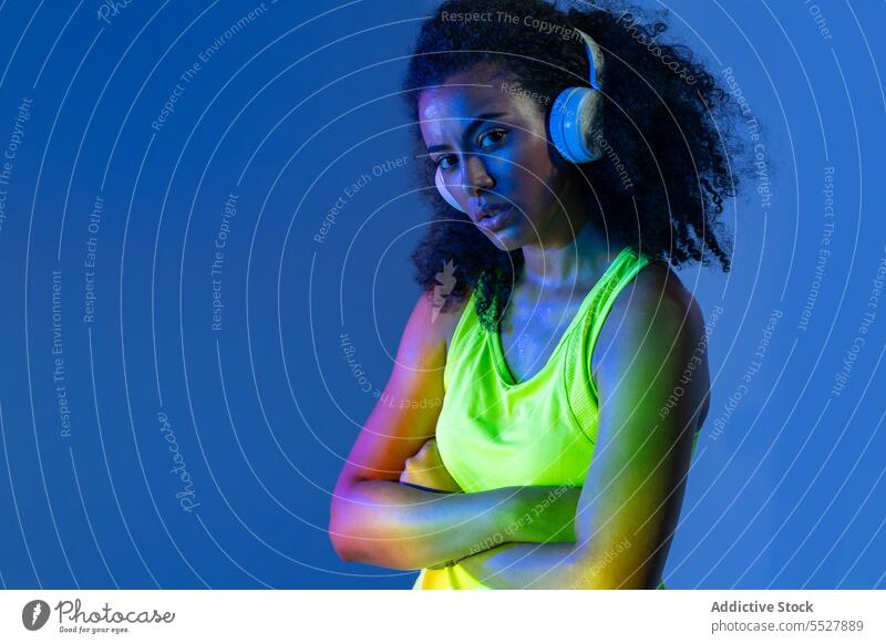 Schwarze Frau mit Kopfhörern im Stehen Studioaufnahme Sport zuhören Musik Fitness Audio Melodie schwarz Sportlerin meloman ethnisch Klang Sportkleidung Wellness