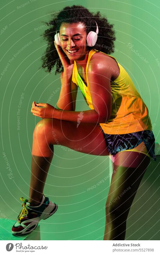 Verführerische ethnische Frau in Aktivkleidung Kopfhörer Studioaufnahme Sport zuhören Musik Fitness schwarz Audio Melodie Sportlerin Afroamerikaner meloman