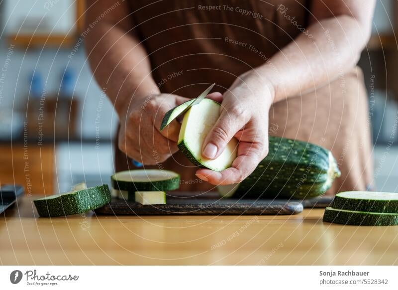 Eine Frau schält einen Zucchini auf einem Schneidebrett in einer Küche. Gemüse Essen zubereiten schälen Lebensmittel Mittagessen Vegetarische Ernährung