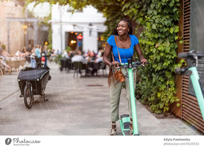 Porträt einer glücklichen jungen Frau auf einem Elektroroller in der Stadt Erwachsener attraktiv schön schwarz Selbstvertrauen selbstbewusst cool Mädchen Frisur