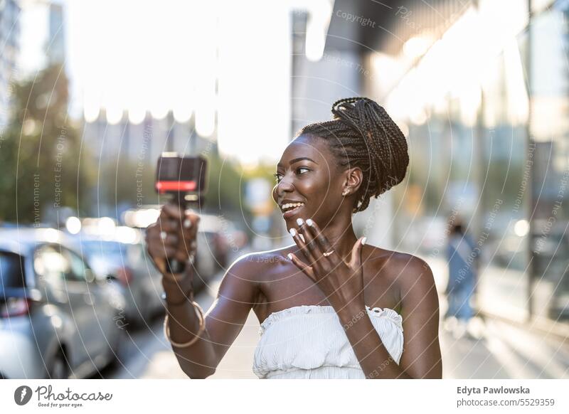 Junge Frau nimmt ein Video mit einer Kamera in einer Stadt auf Erwachsener attraktiv schön schwarz Selbstvertrauen selbstbewusst cool Mädchen Frisur Freizeit