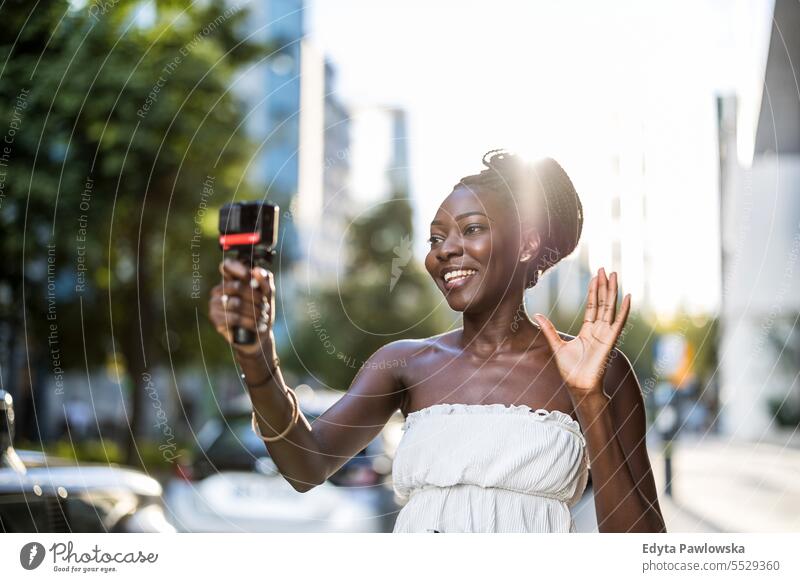 Junge Frau nimmt ein Video mit einer Kamera in einer Stadt auf Erwachsener attraktiv schön schwarz Selbstvertrauen selbstbewusst cool Mädchen Frisur Freizeit