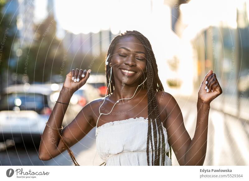 Junge Frau hört Musik mit Kopfhörern in der Stadt Erwachsener attraktiv schön schwarz Selbstvertrauen selbstbewusst cool Mädchen Frisur Freizeit Lifestyle