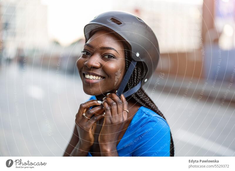 Junge Frau setzt ihren Fahrradhelm auf Erwachsener attraktiv schön schwarz Selbstvertrauen selbstbewusst cool Mädchen Frisur Freizeit Lifestyle natürlich