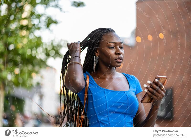 Porträt einer jungen Frau beim Telefonieren in der Stadt Erwachsener attraktiv schön schwarz Selbstvertrauen selbstbewusst cool Mädchen Frisur Freizeit