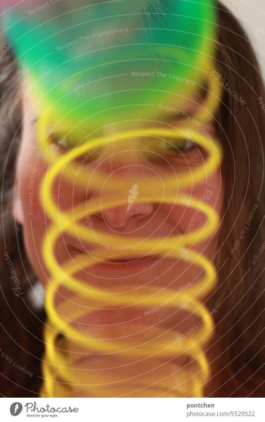 eine grün und gelbe spirale  vor dem  gesicht einer lächelnden frau. lustig bunt bewegung regenbogen spielzeug chaos gedankenkreisen
