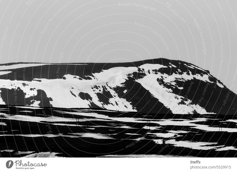 Skigebiet auf einer Bergseite auf Island Skipiste Skisaison Saisonende isländisch Felshügel Hügel Hügelseite Skilift Schneeflecken Schneereste Nordostisland