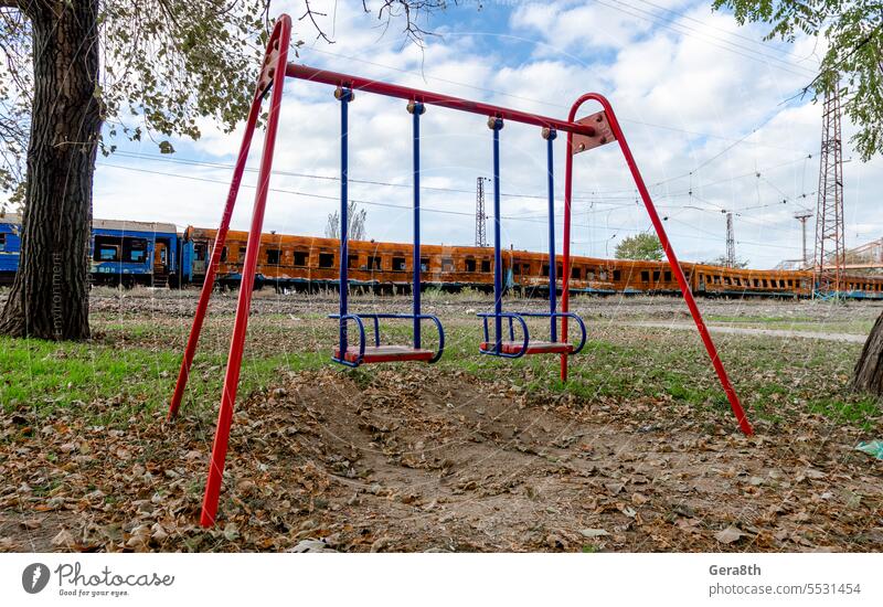 leere Schaukeln auf einem leeren Spielplatz ohne Menschen vor dem Hintergrund verbrannter Züge in der Ukraine donezk Kherson kyiv Lugansk mariupol Russland