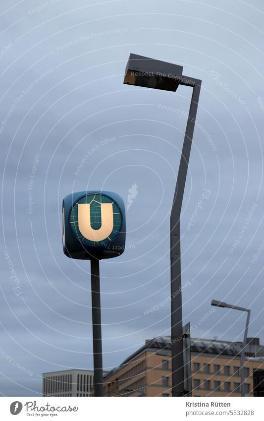 geknickte straßenlaterne an beleuchtetem u U u-bahn ubahn haltestelle station leuchtschild hinweis markierung typografie eingang ausgang transport