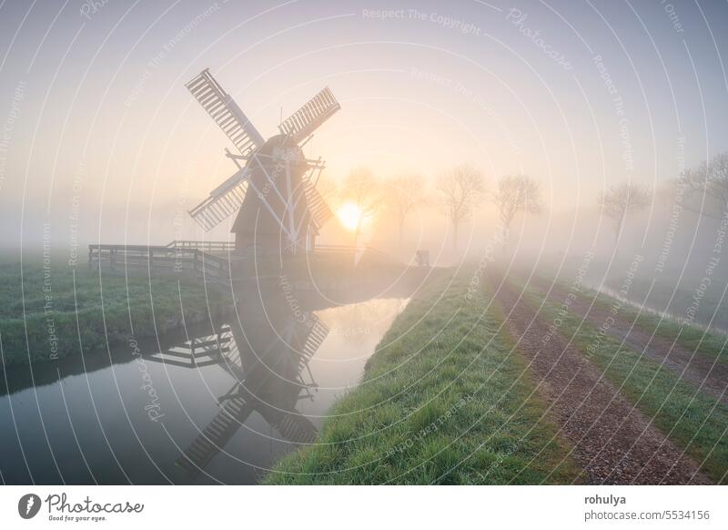 schöner nebliger Sonnenaufgang in holländischer Landschaft mit Windmühle Architektur Nebel Sonnenlicht Sonnenschein Fluss Kanal Wasser Straße Weg