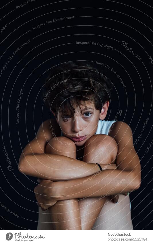 Porträt eines 10-jährigen Jungen mit traurigem Blick, schwarzer Hintergrund jung 10 Jahre alt lässig verärgert deprimiert psychische Gesundheit mental Kaukasier
