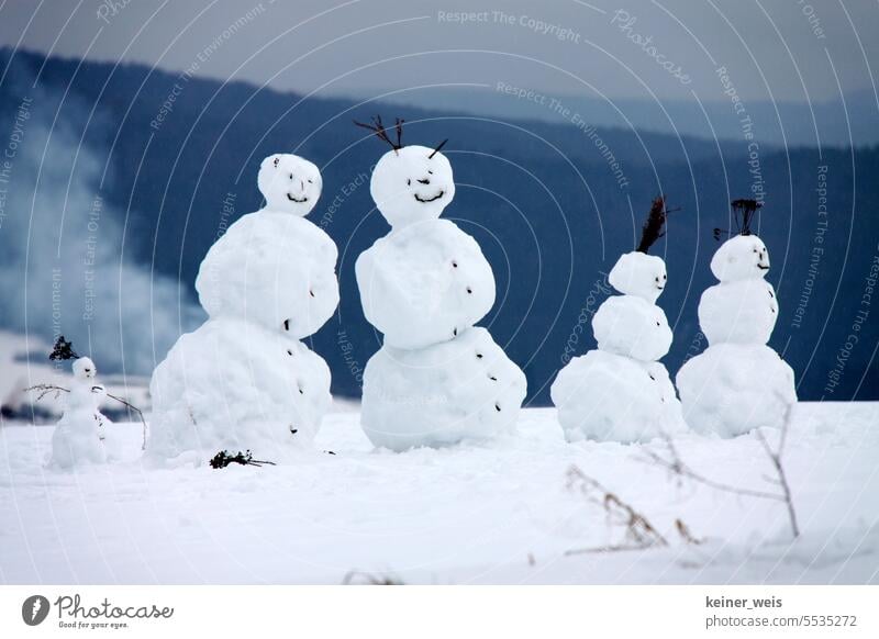 Schneefrau und Schneemann mit ihren Schneekindern als idyllisches Familienbild der Schneemannfamilie im Winter Schneefamilie Jahreszeiten Spielen Außenaufnahme