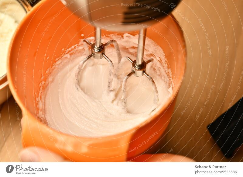 Eischnee oder Sahne wird mit einem Rührgerät in einer orangenen Rührschüssel geschlagen Backen zubereiten Küche kochen rühren Schneebesen backen Teigwaren