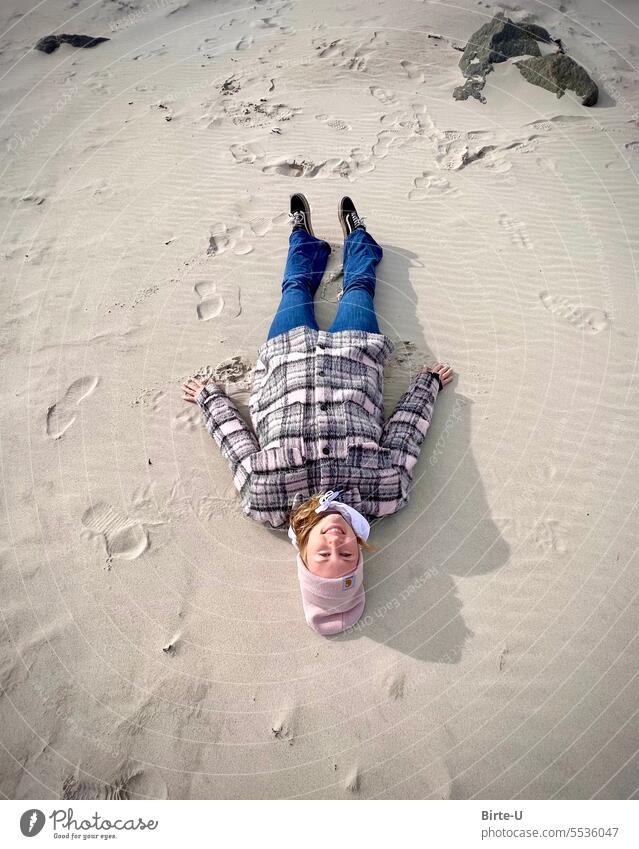 Junge Frau liegt im Sand am Strand reisen Urlaub Herbst Winter Freude Lebensfreude strahlend Natur Küste Farbfoto Tag