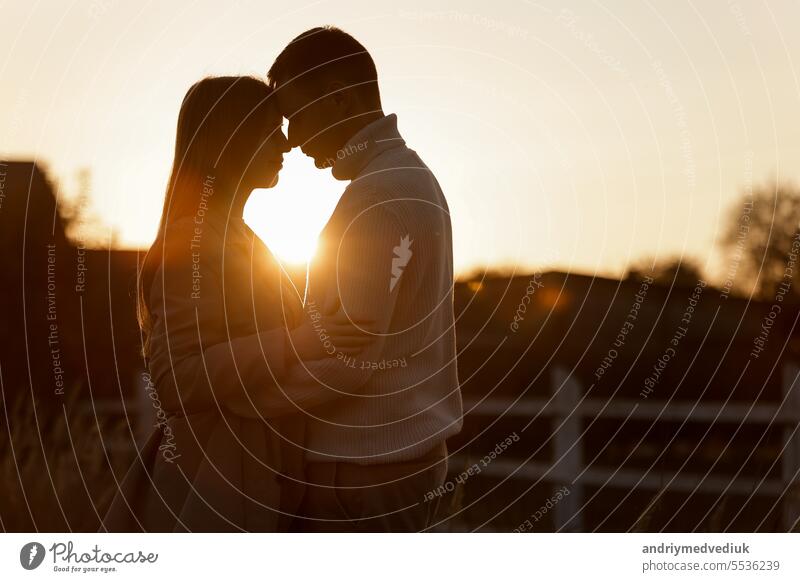 Silhouette der liebenden Paar Paar bei Sonnenuntergang umarmt und berühren Nase an Nase im Freien im Park. Junger Mann und Frau fallen in der Liebe haben romantisches Datum am Valentinstag