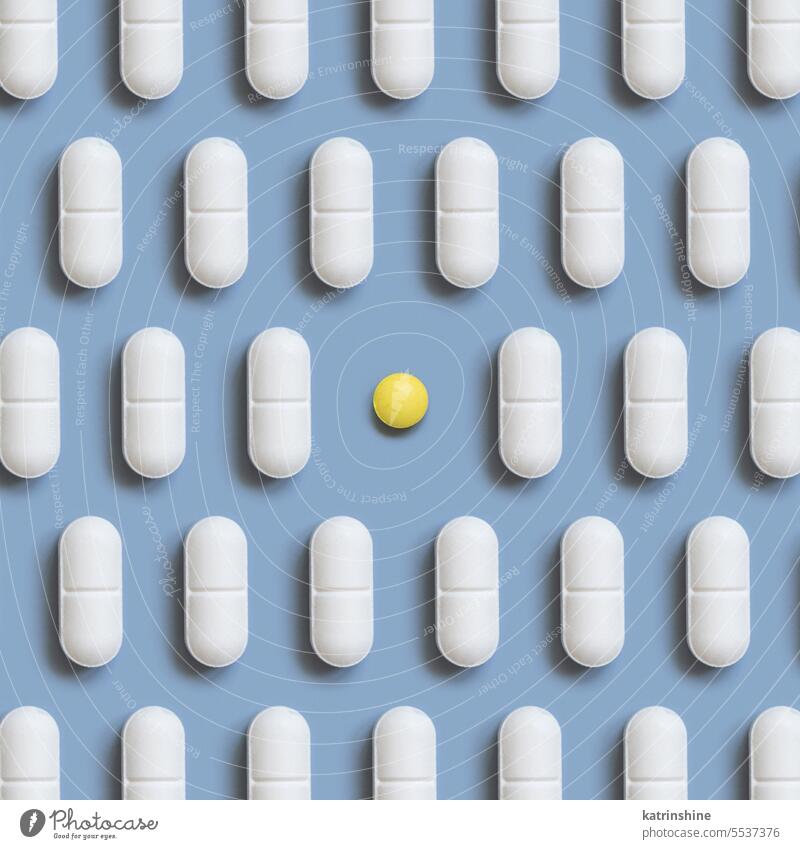 Mischung aus weißen medizinischen Pillen in einer Reihe mit einer gelben auf hellblauer Draufsicht. Nahrungsergänzungsmittel Medizin Pharma Kapseln Linie