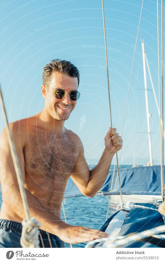 Glücklicher gut aussehender Mann auf einem Segelboot auf dem Meer Jacht Lächeln Boot Sommer Urlaub selbstbewusst Kreuzfahrt Körper Träumer stylisch Gefäße Model