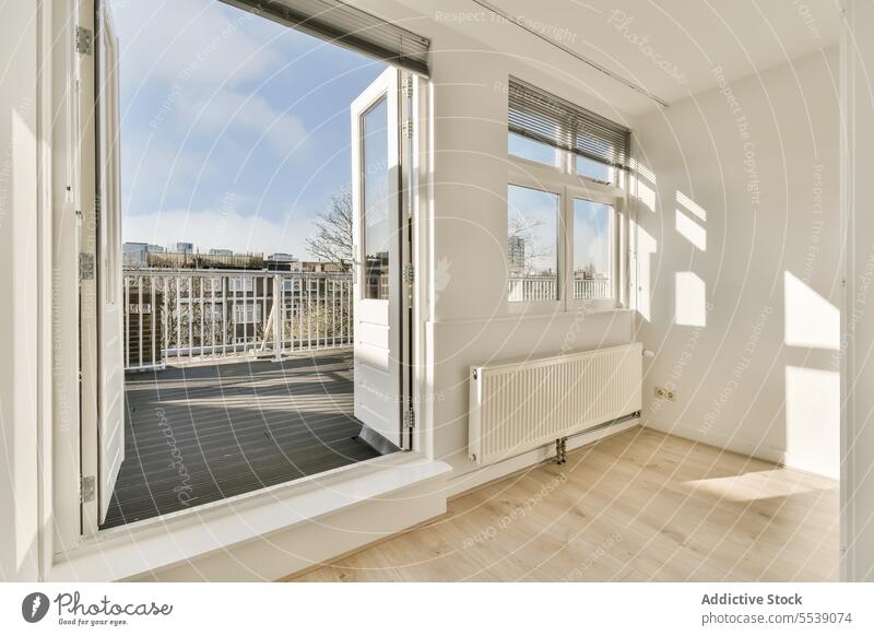 Weißes Zimmer mit Fenster und Tür zum Balkon Raum weiß modern Appartement sonnig Innenbereich Heizkörper Sonnenlicht Stock Reling Schatten Wand Textfreiraum