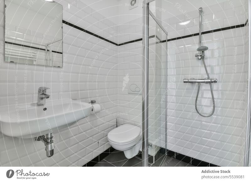 Badezimmer mit Toilettenbecken und Dusche an der gefliesten Wand Schalen & Schüsseln Waschbecken Wasserhahn Spiegel weiß Fliesen u. Kacheln modern Appartement