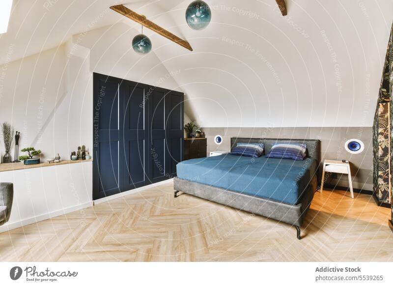 Schlafzimmer mit blauem Bett und großem Kleiderschrank stylisch Innenbereich bequem Kopfkissen Hartholz Stock weiß Wand heimwärts Appartement modern