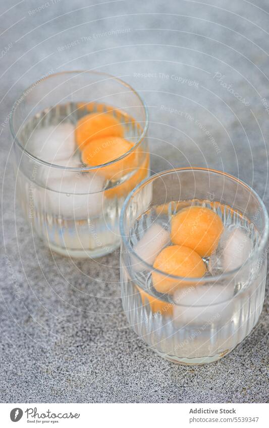 Glas mit Melonenkugeln in eisgekühltem Getränk auf der Oberfläche Paar trinken durchsichtig Eis dienen Cocktail Tageslicht frisch hell Erfrischung kalt