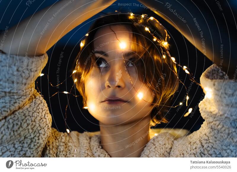 Porträt einer kurzhaarigen Frau mit Lichtern auf dem Kopf Schnur beleuchtet verwickelt Nacht dunkel Abend elektrisch Kurze Haare Weihnachtsbeleuchtung